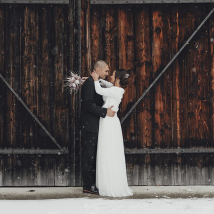 Ehepaar vor Holztoor im Winter, Hochzeitsplanung München